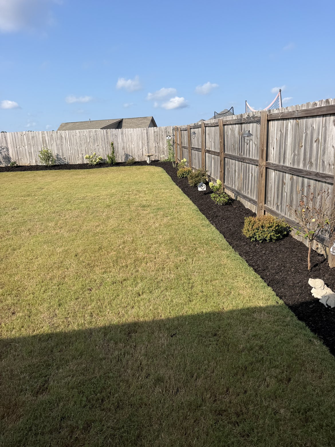 Same backyard bed after fresh dark mulch installation with clean edges